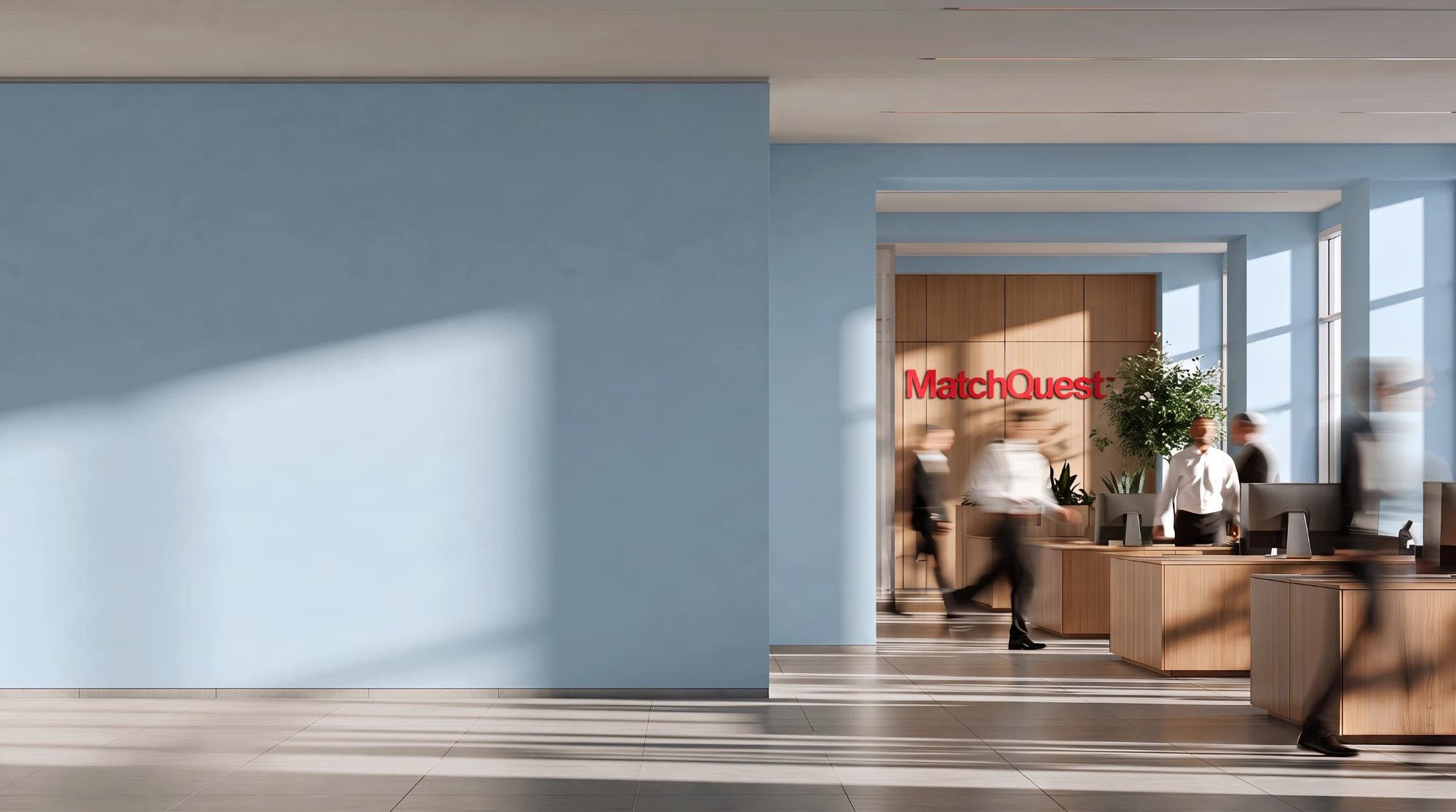 The MatchQuest office in morning light: staff at their desks beneath the red MatchQuest sign.